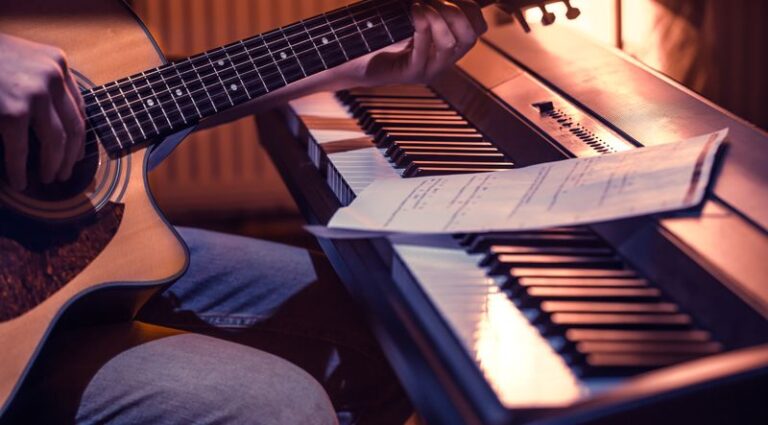man playing acoustic guitar and piano close-up, recording notes